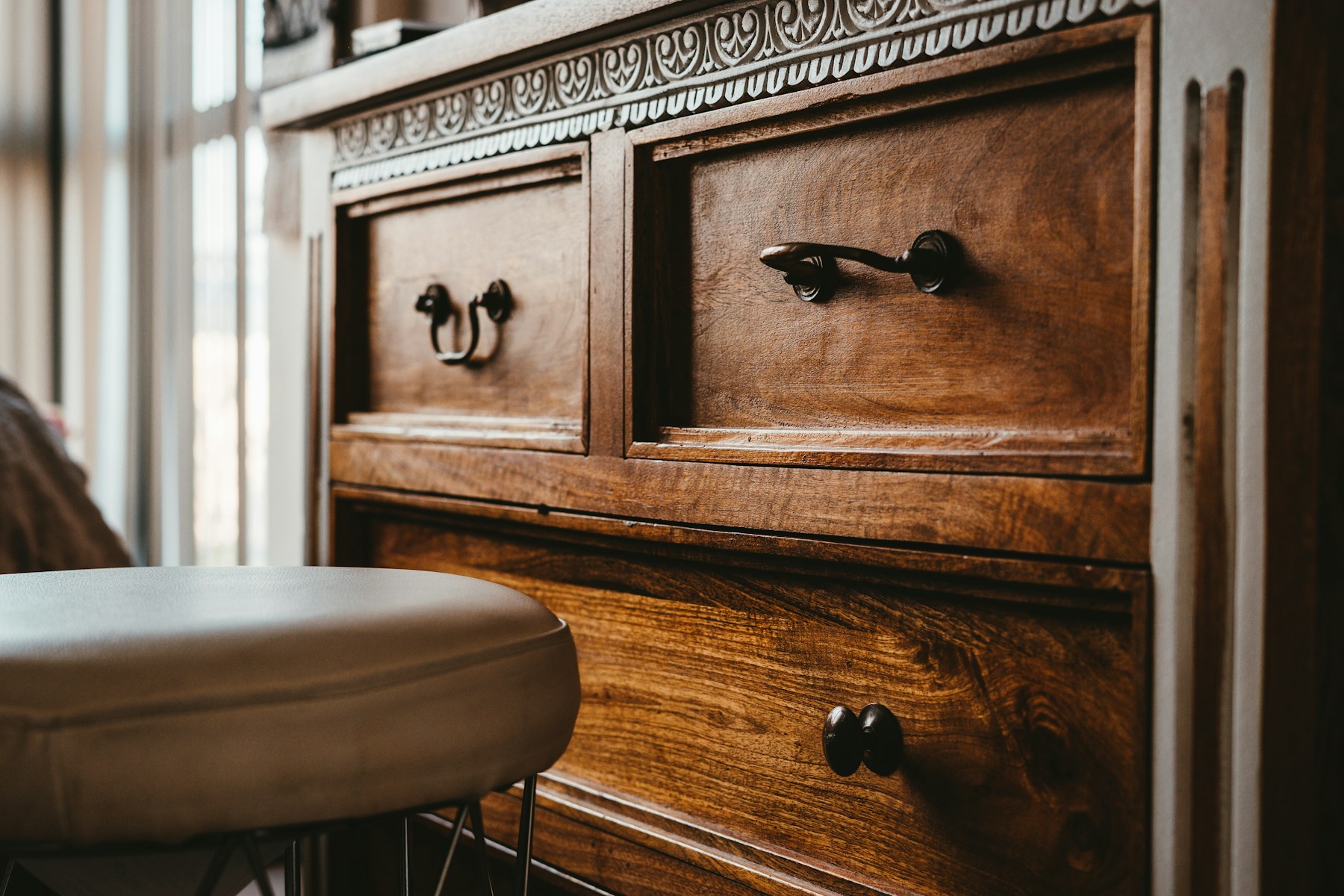 A dark carved wooden chest of drawers with iron pulls