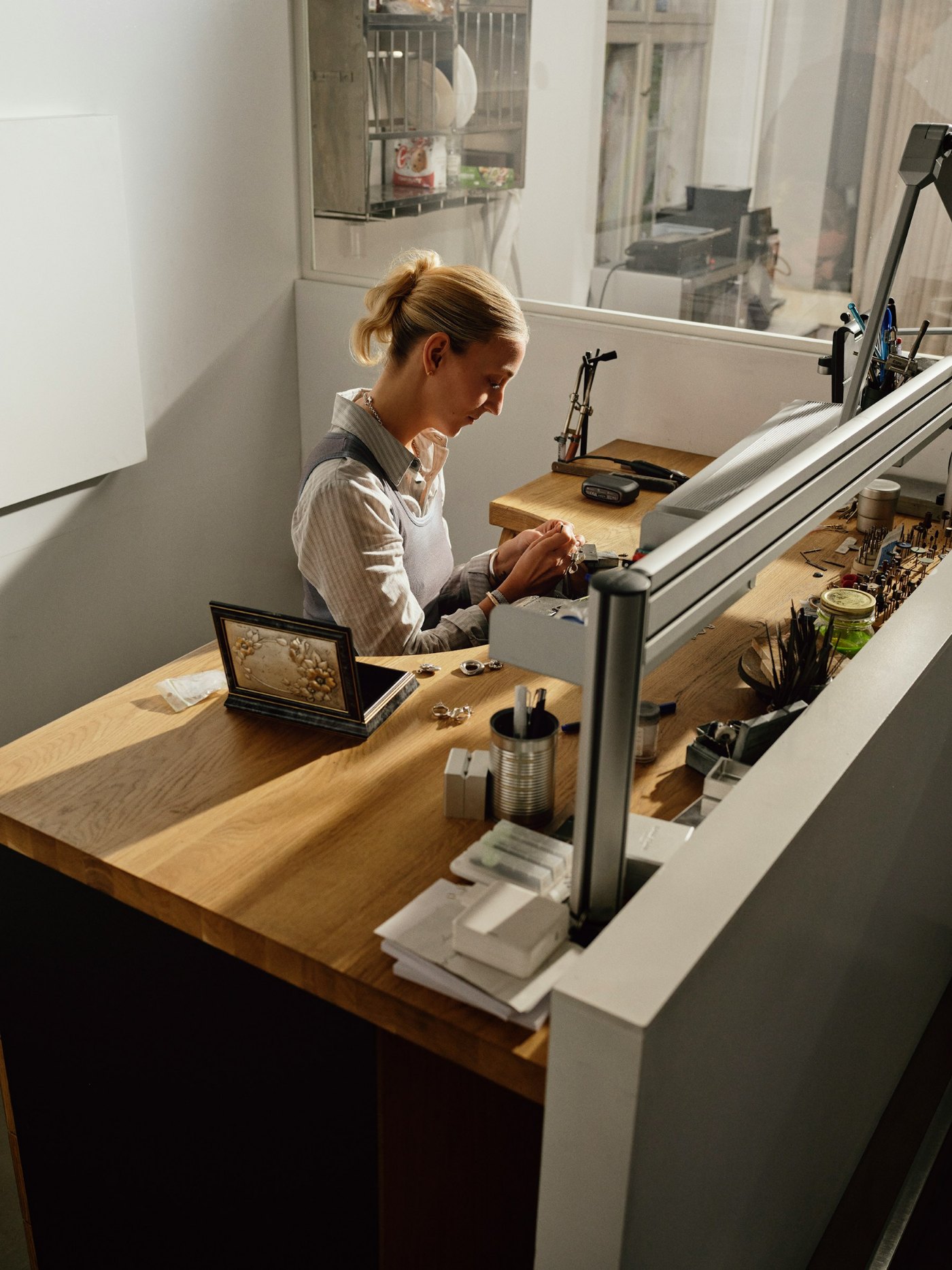 A maker working with small tools at a lit workbench